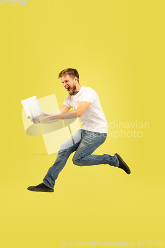 Image of Full length portrait of happy jumping man on yellow background