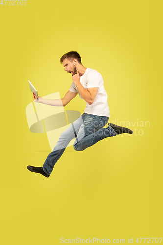 Image of Full length portrait of happy jumping man on yellow background