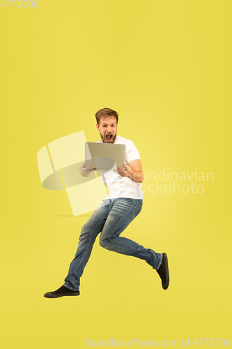 Image of Full length portrait of happy jumping man on yellow background