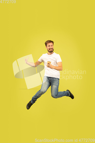 Image of Full length portrait of happy jumping man on yellow background