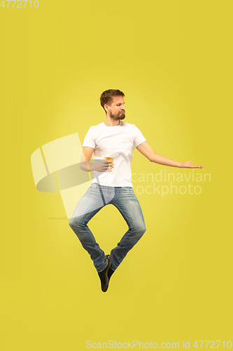 Image of Full length portrait of happy jumping man on yellow background