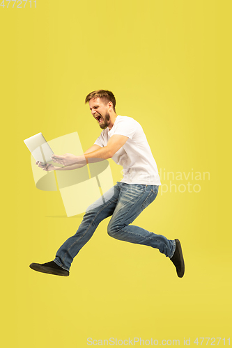 Image of Full length portrait of happy jumping man on yellow background