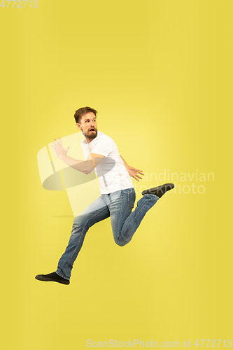 Image of Full length portrait of happy jumping man on yellow background