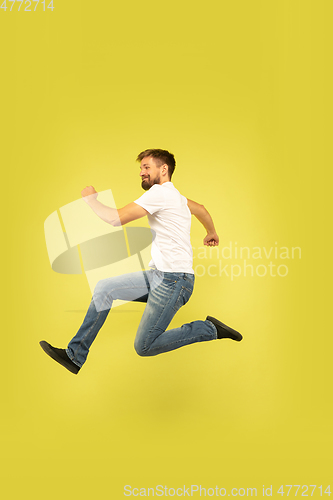 Image of Full length portrait of happy jumping man on yellow background