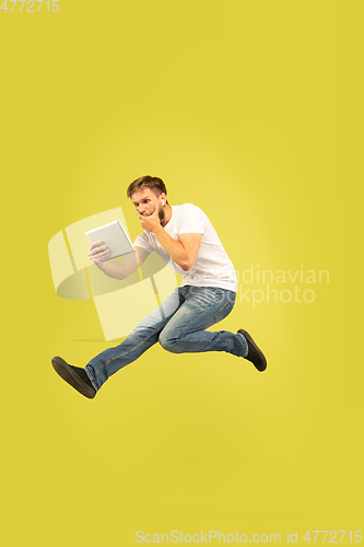 Image of Full length portrait of happy jumping man on yellow background