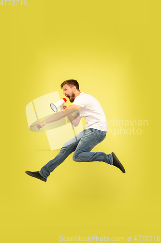 Image of Full length portrait of happy jumping man on yellow background