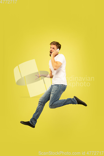 Image of Full length portrait of happy jumping man on yellow background