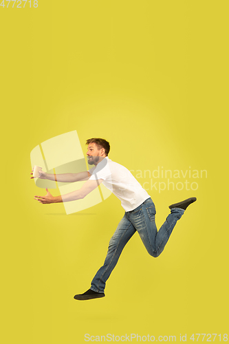 Image of Full length portrait of happy jumping man on yellow background