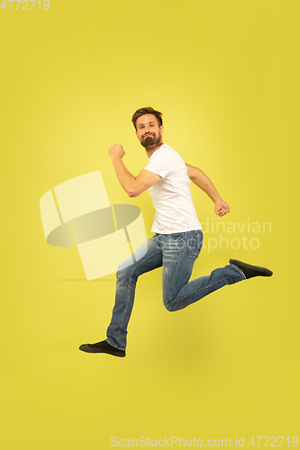 Image of Full length portrait of happy jumping man on yellow background