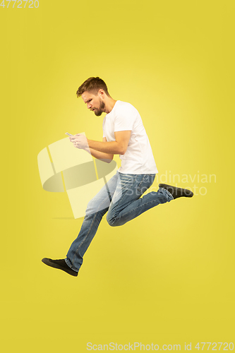 Image of Full length portrait of happy jumping man on yellow background