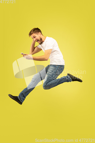 Image of Full length portrait of happy jumping man on yellow background