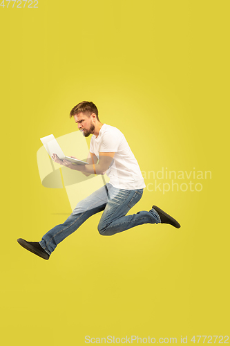 Image of Full length portrait of happy jumping man on yellow background