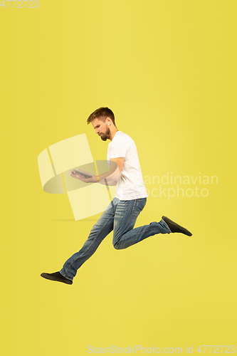 Image of Full length portrait of happy jumping man on yellow background