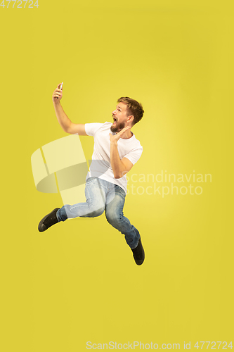 Image of Full length portrait of happy jumping man on yellow background