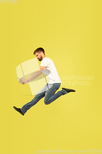 Image of Full length portrait of happy jumping man on yellow background