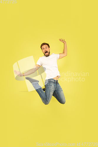 Image of Full length portrait of happy jumping man on yellow background