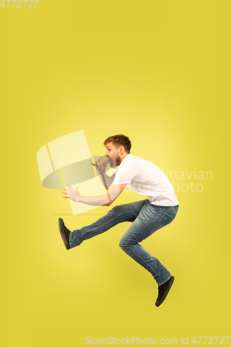 Image of Full length portrait of happy jumping man on yellow background