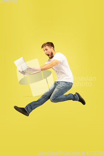 Image of Full length portrait of happy jumping man on yellow background