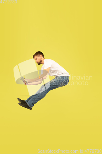 Image of Full length portrait of happy jumping man on yellow background