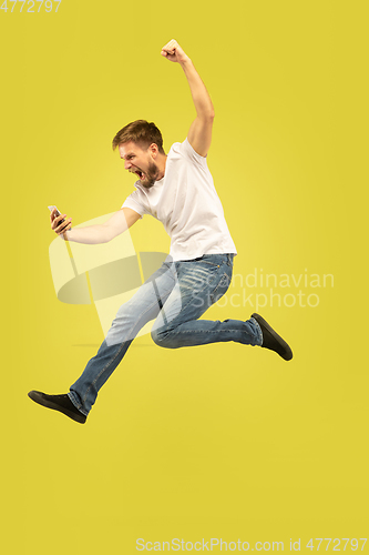 Image of Full length portrait of happy jumping man on yellow background