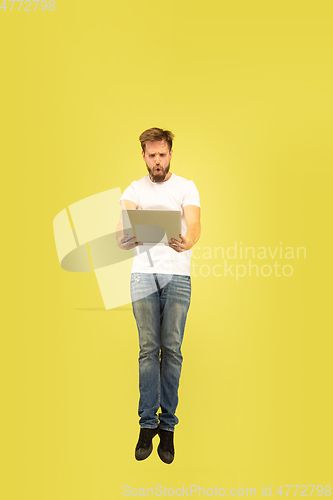 Image of Full length portrait of happy jumping man on yellow background