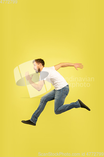 Image of Full length portrait of happy jumping man on yellow background