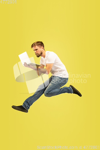 Image of Full length portrait of happy jumping man on yellow background