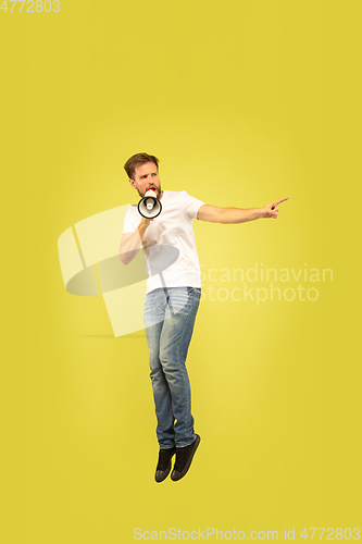 Image of Full length portrait of happy jumping man on yellow background