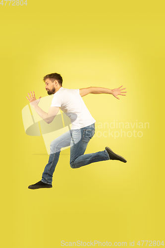 Image of Full length portrait of happy jumping man on yellow background