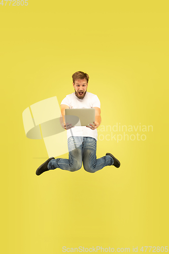 Image of Full length portrait of happy jumping man on yellow background