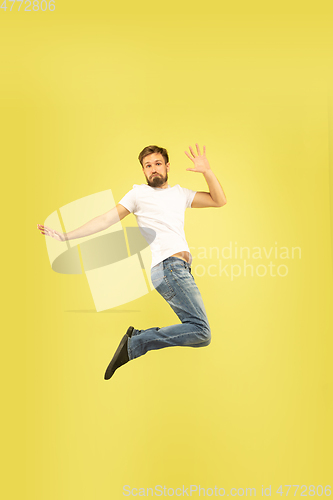 Image of Full length portrait of happy jumping man on yellow background