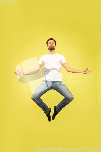 Image of Full length portrait of happy jumping man on yellow background