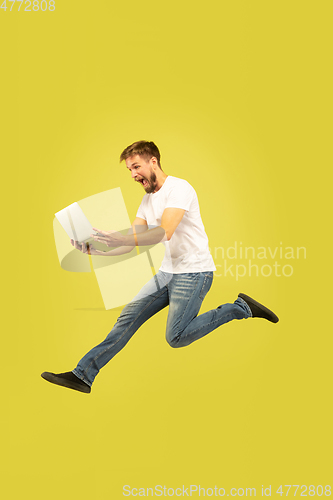 Image of Full length portrait of happy jumping man on yellow background