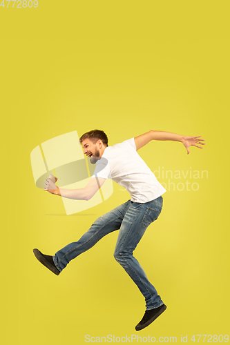 Image of Full length portrait of happy jumping man on yellow background