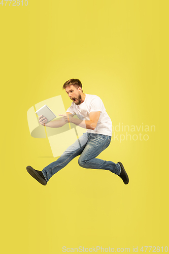 Image of Full length portrait of happy jumping man on yellow background