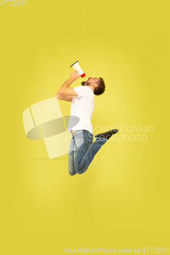 Image of Full length portrait of happy jumping man on yellow background