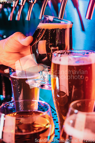 Image of Hand of bartender pouring a large lager beer in tap