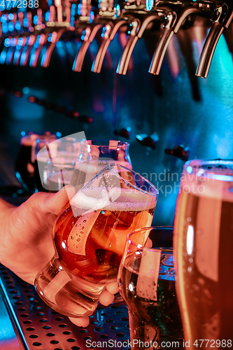 Image of Hand of bartender pouring a large lager beer in tap