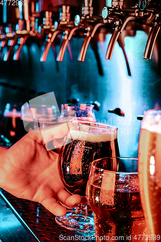 Image of Hand of bartender pouring a large ale, porter, stout beer in tap