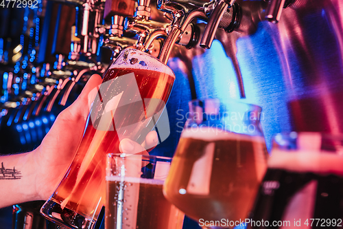 Image of Hand of bartender pouring a large lager beer in tap