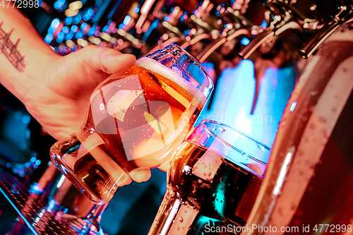 Image of Hand of bartender pouring a large lager beer in tap