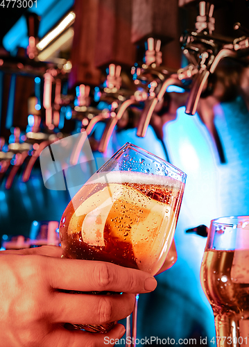 Image of Hand of bartender pouring a large lager beer in tap