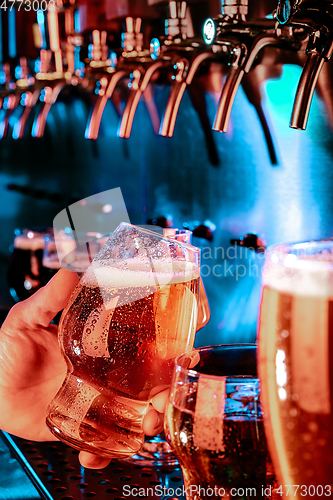 Image of Hand of bartender pouring a large lager beer in tap