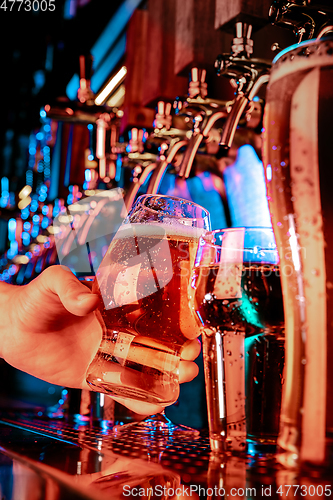 Image of Hand of bartender pouring a large lager beer in tap