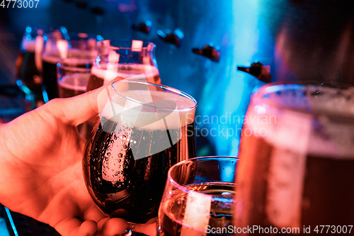 Image of Hand of bartender pouring a large ale, porter, stout beer in tap