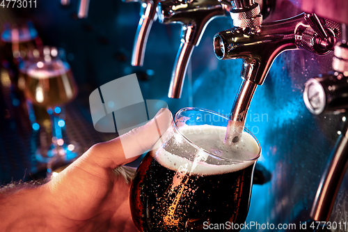 Image of Hand of bartender pouring a large ale, porter, stout beer in tap