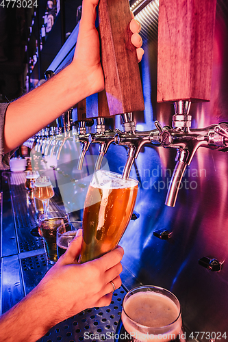 Image of Hand of bartender pouring a large lager beer in tap