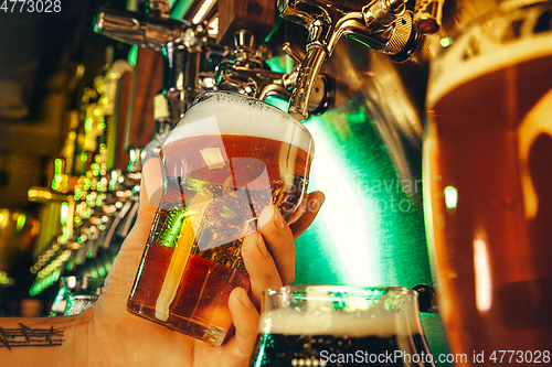 Image of Hand of bartender pouring a large lager beer in tap