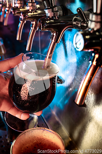 Image of Hand of bartender pouring a large ale, porter, stout beer in tap