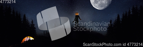 Image of Halloween theme: scary maniac with pumpkin head in dark forest